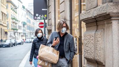 Pedestrians wearing protective face masks walk past shops in Milan, Italy. Bloomberg