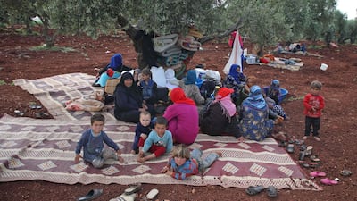 Displaced Syrians gather under the shade of a tree in a field near a camp in the village of Atme. AFP