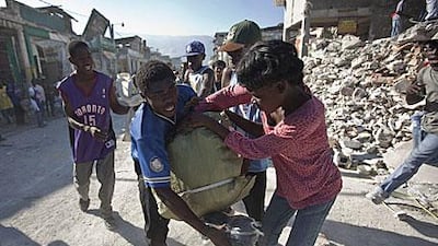 People fight over goods scavenged from the rubble of collapsed buildings in Port-au-Prince.