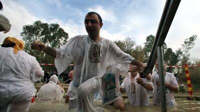 A man emerges from the River Jordan site after his baptism in its waters on the Feast of the Epiphany.