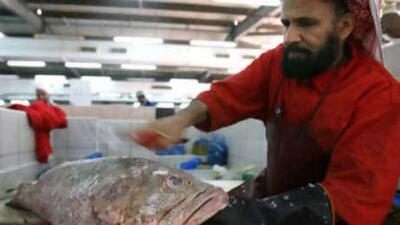 A trader de-scales hamour at the Abu Dhabi fish market. Consumers are encouraged to reject small fish that were caught too early and could not reproduce to sustain their species.