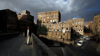 A Yemeni walks through a pedestrian bridge in front of historic buildings in the old city of Sanaa, Yemen. EPA