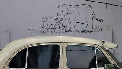An Ambassador car stands parked in front of a graffiti on a wall in Bangalore.