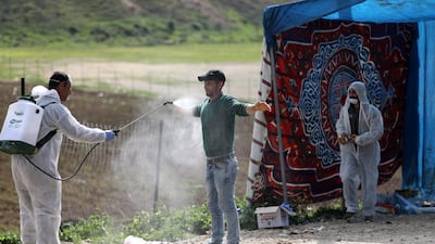 An employee of the Palestinian health ministry sprays disinfectant on a worker crossing back from Israel at the checkpoint of Tarqumiya, near the West Bank town of Hebron. EPA
