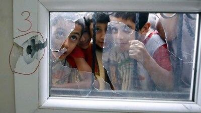 Turkish boys look through a shattered window after an anti-aircraft shell fired from Syria hit a health centre across the border in the Reyhanli district of Turkey's Hatay province.