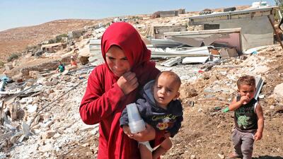 A Palestinian woman walks carrying a child past wreckage of mobile homes built by EU funding and destroyed by Israeli forces in the village of Mufagara south of Yatta near Hebron in the occupied West Bank. AFP