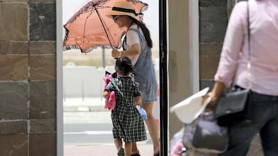 A woman uses a parasol to protect herself from the elements on a blustery day in Dubai. Chris Whiteoak / The National