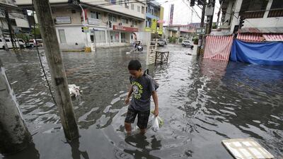 A man wades along a flooded street caused by rains from Typhoon Nock-Ten in Quezon city, north of Manila. Aaron Favila / AP