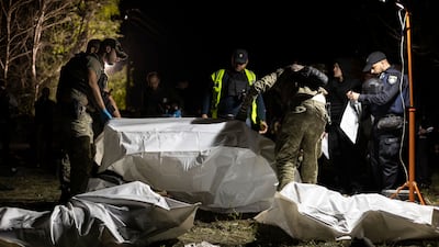 Ukrainian policemen inspect bodies after a Russian rocket attack that killed 51 people in the village of Hroza near Kharkiv, Ukraine. AP