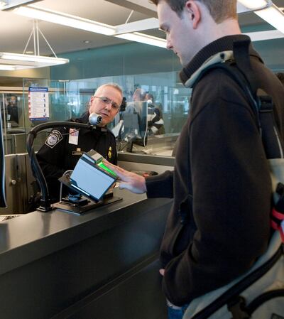 A Homeland Security officer instructs a traveller as he is fingerprinted using a biometric scanner at the JFK International Airport in New York, US, on March 25, 2008. Photo via Newscom