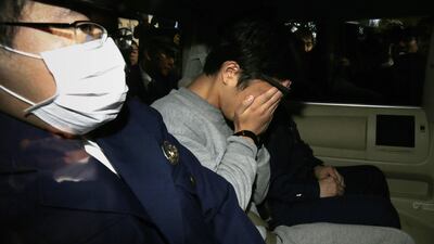 Suspect Takahiro Shiraishi (C) covers his face with his hands as he is transported to the prosecutor's office from a police station in Tokyo on November 1, 2017. The 27-year-old Japanese man, who was arrested after police found nine dismembered corpses rotting in his house, has confessed to killing all his victims over a two-month spree after contacting them via Twitter, media reports. / AFP PHOTO / JIJI PRESS / STR / Japan OUT
