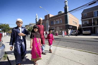 Muslim children walk with their father past a mosque after the completion of a service for the Eid al-Adha holiday in the Queens borough of New York. AP