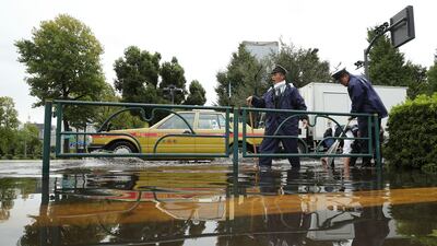 Policemen remove leaves from a drain on a flooded road in Tokyo on October 23, 2017. AFP