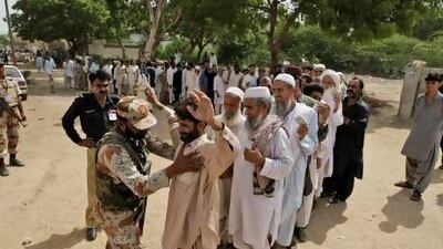 A soldier frisks voters before they enter a polling station in Karachi. Fareed Khan / AP Photo