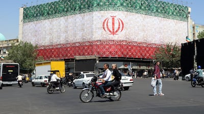 Iranians drive past a billboard featuring Iran's national flag at Enqelab Square in Tehran on Sunday. EPA