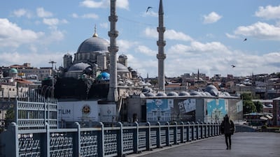 A journalist wearing a protective face mask walks on the Galata bridge on the Bosphorus backdropped by New mosque during a curfew amid the ongoing pandemic of the Covid-19 disease caused by the Sars-CoV-2 coronavirus in Istanbul, Turkey, 23 May 2020. EPA