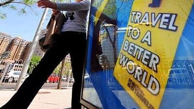 A woman walks past an advertising billboard promoting a global travel magazine in Beiijng. AFP