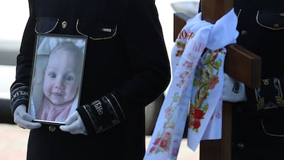 A mourner clutches a picture at the funeral of 3-month-old Kira Glodan. The service was also in memory of her mother and grandmother. All three were among eight people killed in Odesa, Ukraine when a Russian missile hit a residential building. AFP