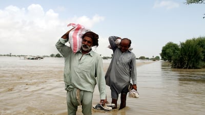 Displaced people carrying food aid wade through floodwaters in Rajanpur, Punjab province. Flooding has caused more than $10 billion in damage across Pakistan. AP