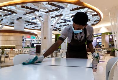 A member of staff wipes down the food court at Yas Mall in Abu Dhabi. Victor Besa / The National
