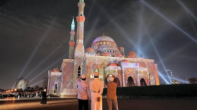 People taking photos of the Al Noor Masjid during the Sharjah Light Festival in Sharjah. Pawan Singh / The National