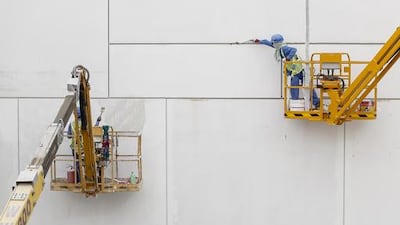 Labourers repair minor imperfections to the ultra-high performance fibre reinforced concrete panels that form the cladding of the Louvre Abu Dhabi. Antoine Robertson / The National