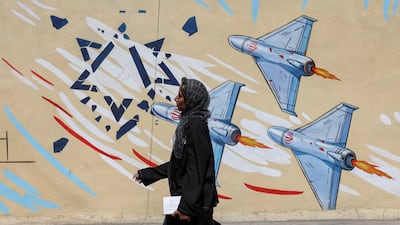 An Iranian woman walks past an anti-Israel mural in Tehran. Reuters