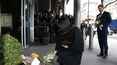 Meghan spent some time reading messages left on floral tributes outside the Commission. AFP