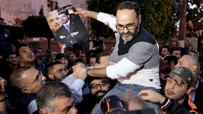 Lebanese actor Ziad Itani holds a picture for Lebanese Prime minister Saad Hariri, as relatives and friends carry him upon his return to his home after he was released by Lebanese authorities, in Beirut, Lebanon, on March 13, 2018. Nabil Mounzer / EPA