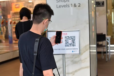 A man scans a QR code before entering a building in Singapore. AP