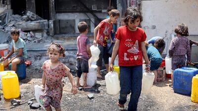 Young Palestinian children fill plastic containers with water on the grounds of a partially destroyed school being used as a shelter in Jabalia refugee camp. AFP