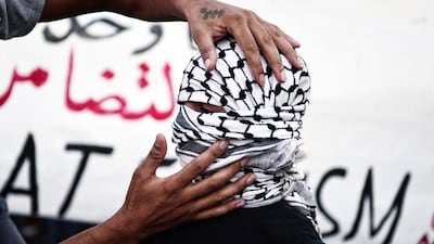 A man adjusts a keffiyeh on a boy's head during a demonstration in support to refugees and migrants in front of Athens municipality building, in Athens. AFP