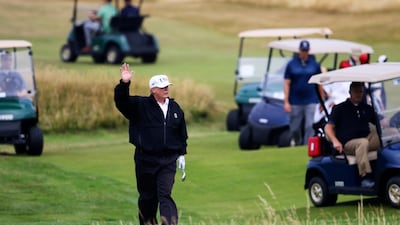 US President Donald Trump waved to protesters while playing golf at Turnberry golf club, Scotland, in 2018. AP