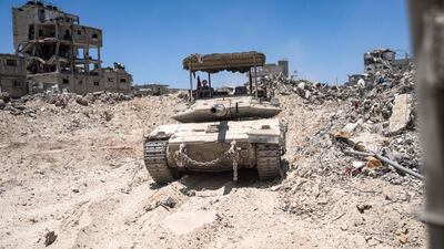 An Israeli tank is seen next to destroyed buildings during a ground operation in southern Gaza. AFP