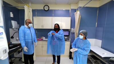 Dr Sanjay Paithankar and his staff wear protective equipment before examining workers at a clinic in Dubai. Dr Paithankar says patients catching Covid-19 a second time, tend to suffer mild to moderate symptom, but for a longer duration than last year. Chris Whiteoak / The National