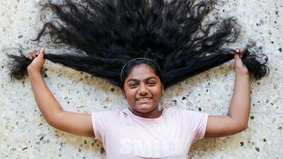 Alina Ahmed,11, is having her hair cut to be used for wigs for cancer patients who have lost their own hair after radiotherapy treatment. Chris Whiteoak / The National