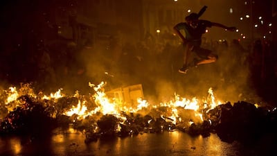A demonstrator with his face covered jumps over a burning barricade during a march in support of teachers on strike in Rio de Janeiro. Felipe Dana / AP