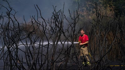 A firefighter battles a grass fire in East London. AP