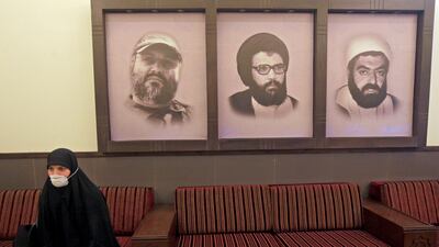 A mask-clad woman sits next to portraits of late Hezbollah leader Abbas Mussawi, late commanders Imad Mughnieh and Ragheb Harb, at a Hezbollah centre in Beirut's southern suburbs. AFP