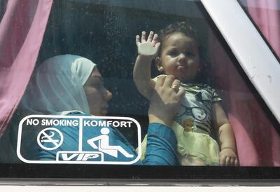 A Syrian refugee sits with her child inside a bus taking her family back to Syria on September 17, 2018. AFP