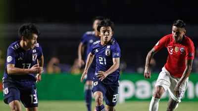 Japan's Takefusa Kubo, centre, is chased by Chile's Erick Pulgar. AFP