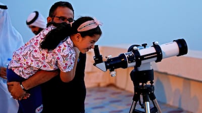 A man helps his daughter to look through a telescope trying to sight the new crescent moon. EPA
