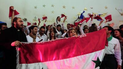 Syrian Christians hold their national flag during a Christmas concert at the Ibrahim Al Khalil Melkite Greek Catholic church in Damascus. Louai Beshara / AFP