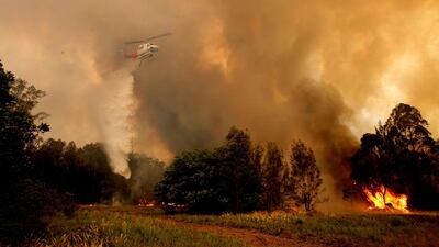 A fire bombing helicopter works to contain a bushfire along Old Bar road in Old Bar, New South Wales, Australia. REUTERS