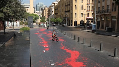 A boy rides his bicycle along a kerb stained with red paint, mimicking blood, as Lebanon marks a national day of mourning. Reuters