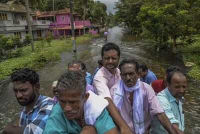 Locals cross the flood water after taking a lift on the rescue truck in Chengannur, India. Getty Images