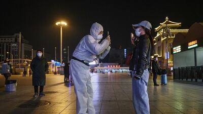 A Chinese man wearing a protective suit takes a photo of a traveller's documents as they arrive at Beijing Railway Station in Beijing, China. Getty Images