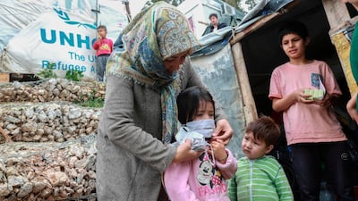 A woman helps a child with a mask after members of NGO "Team Humanity" gave out handmade protective face masks to migrants and refugees in the camp of Moria in the island of Lesbos as as the country is under lockdown. AFP