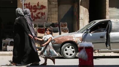 A Syrian girl holds a woman's hand as she walks down a street in the central Syrian rebel-held town of Talbiseh, north of Homs on August 3, 2017. Mahmoud Taha / AFP
