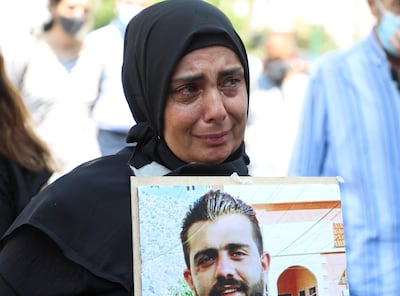 A family member of one of the victims of the 2020 explosion at Beirut port carries a picture during a protest demanding justice on July 9, 2021. Reuters